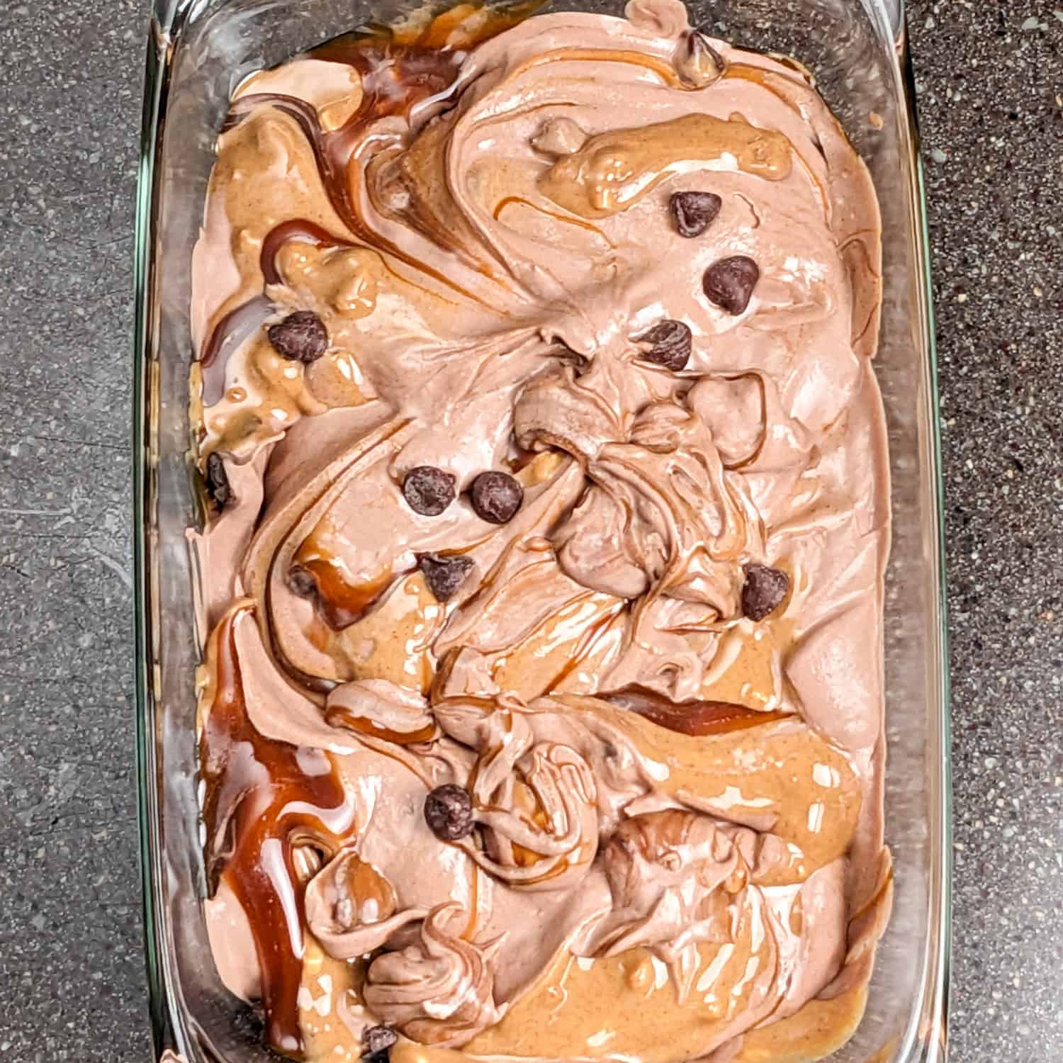 Decadent chocolate peanut butter ice cream swirled with chocolate chips in a glass dish.